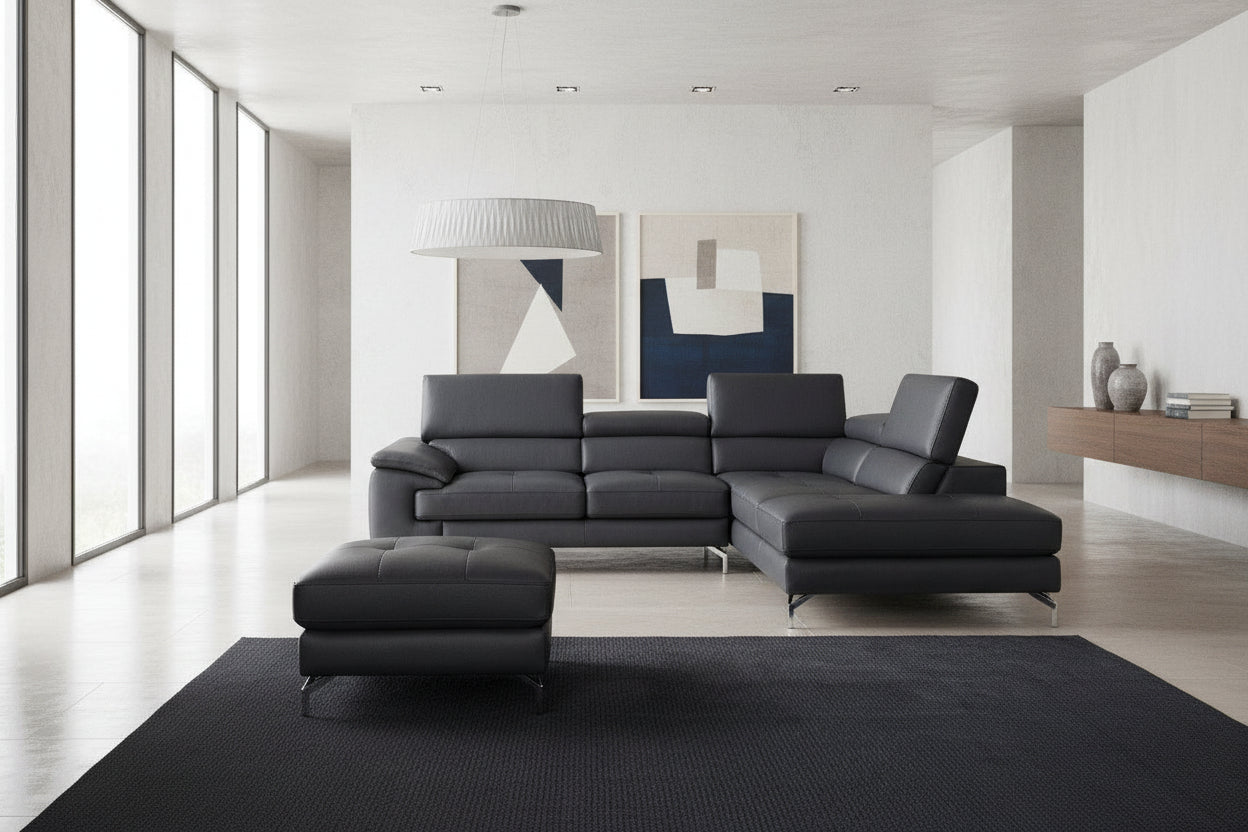 Black leather sectional sofa with ottoman in a room with gray walls and a white ceiling light.