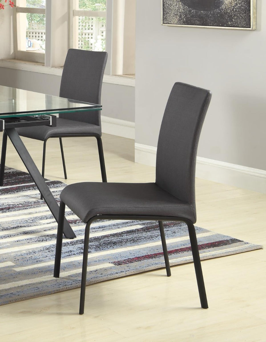 Black chairs in a dining room setting with a glass table and striped rug.