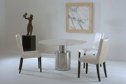 The Athena round dining table and white chairs, featuring a marble-patterned painting on the wall.