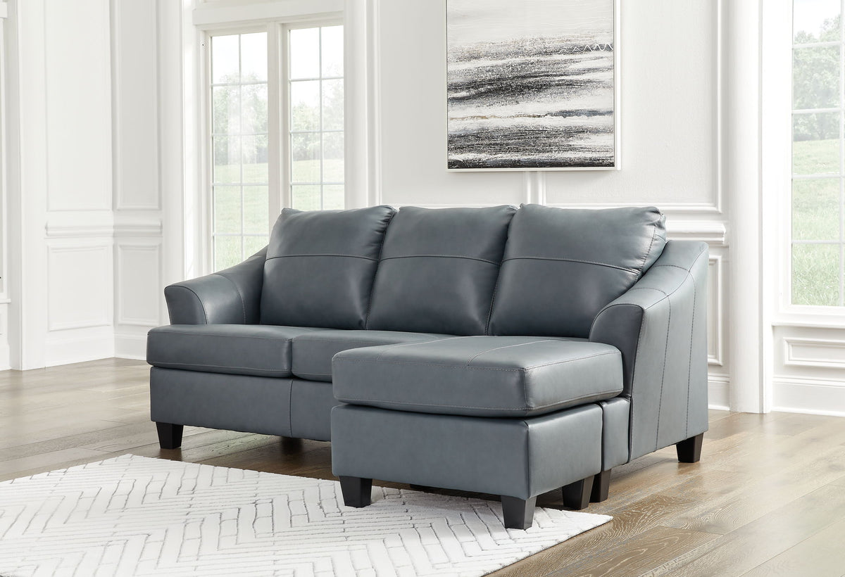 Gray sectional sofa in a living room with large windows and abstract art on the wall.