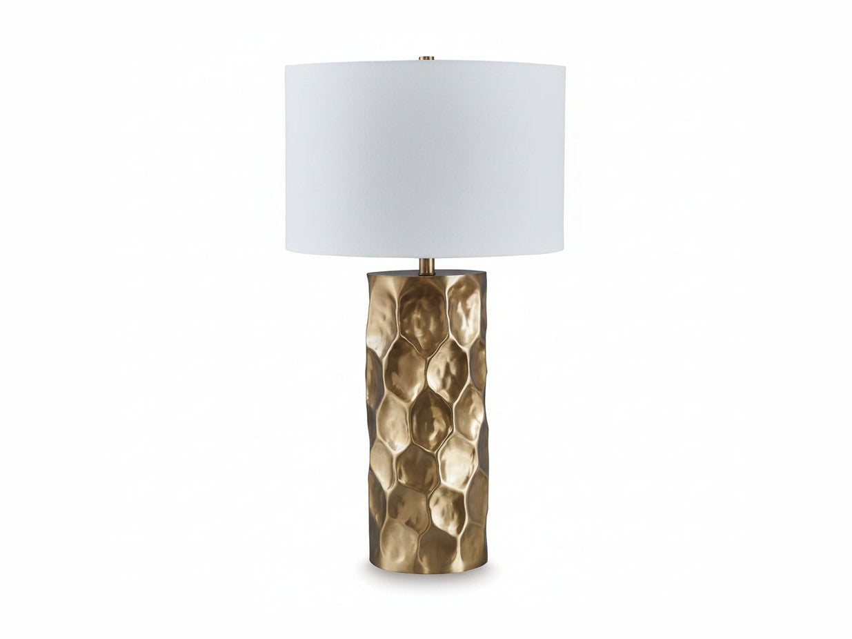 Table lamp with a textured brass base and white shade on a light beige background