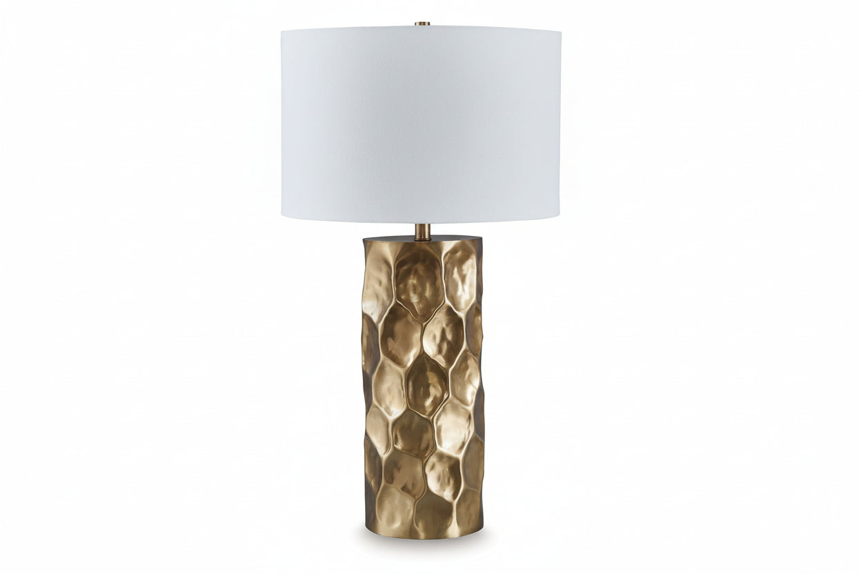 Table lamp with a textured brass base and white shade on a light beige background