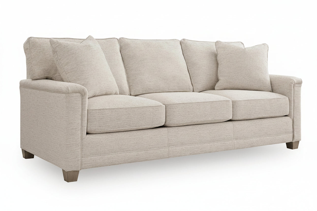A three-seater upholstered sofa in a light beige textured fabric, featuring four loose back cushions, rolled arms, and short dark wooden legs, shown on a white background.