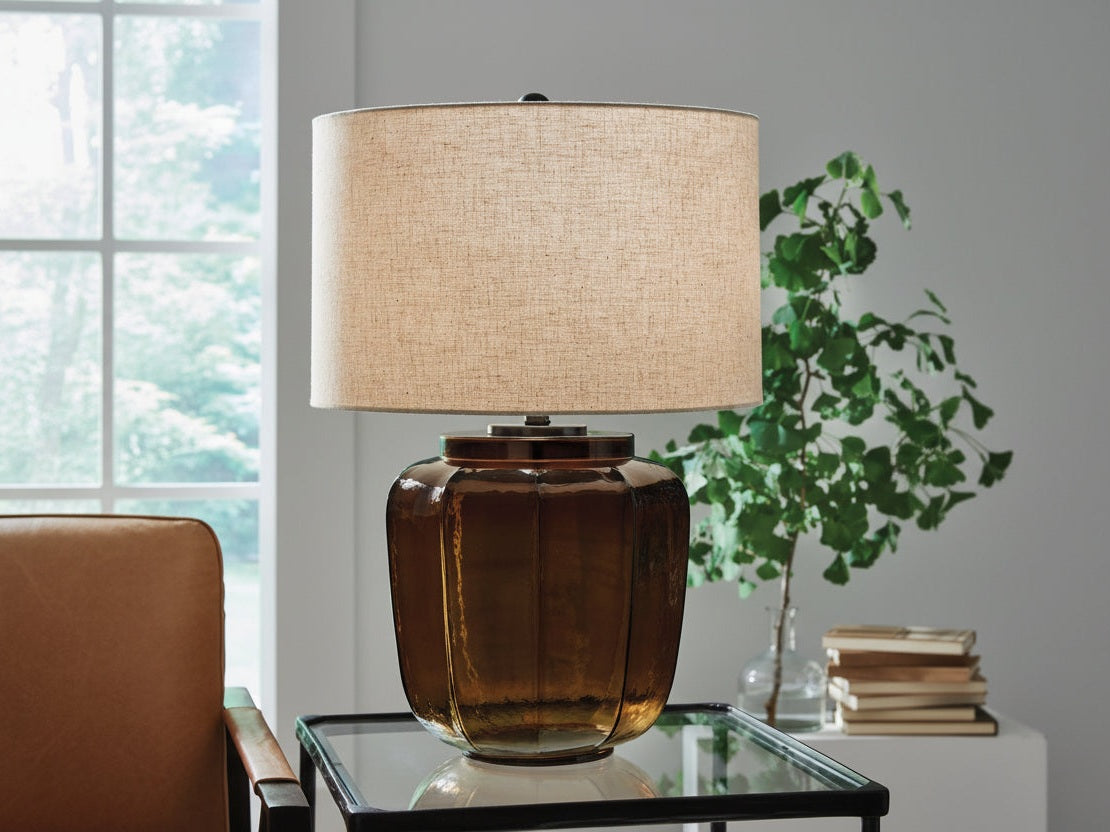 The Bainmore table lamp with a brown base and beige shade is on a glass table.