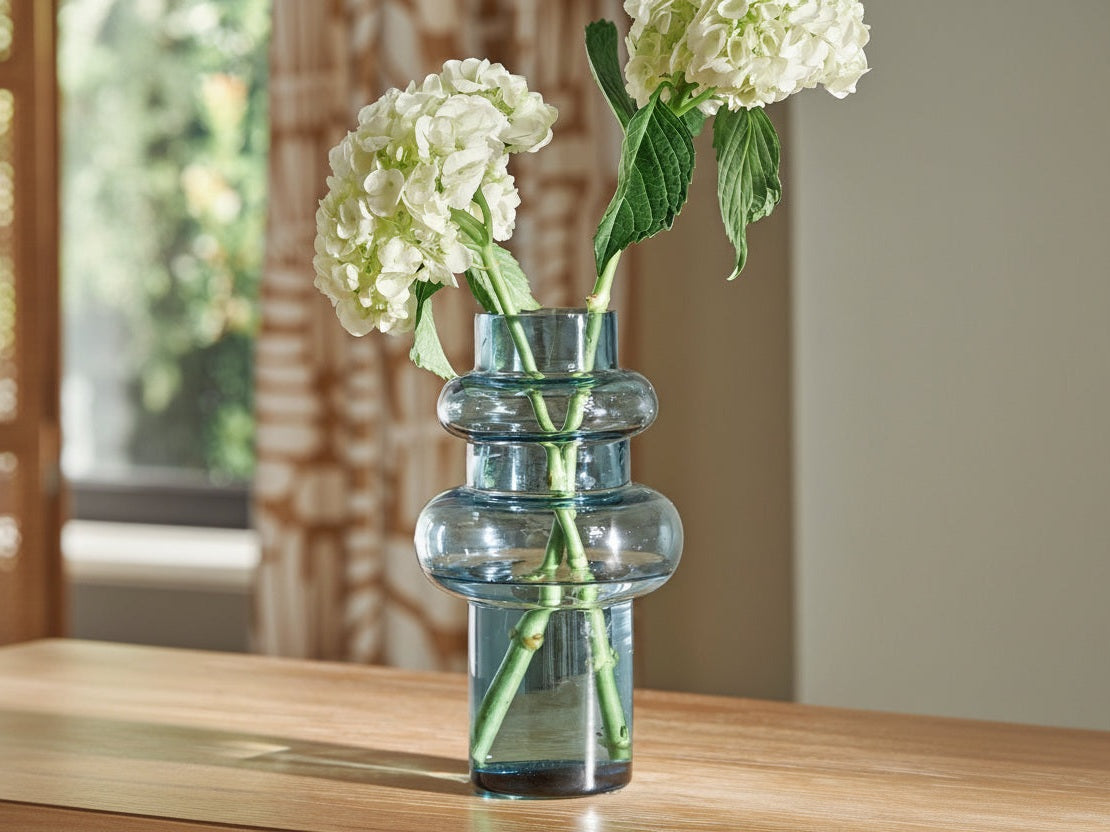 Vallmen clear glass vase with white flowers on a wooden surface.