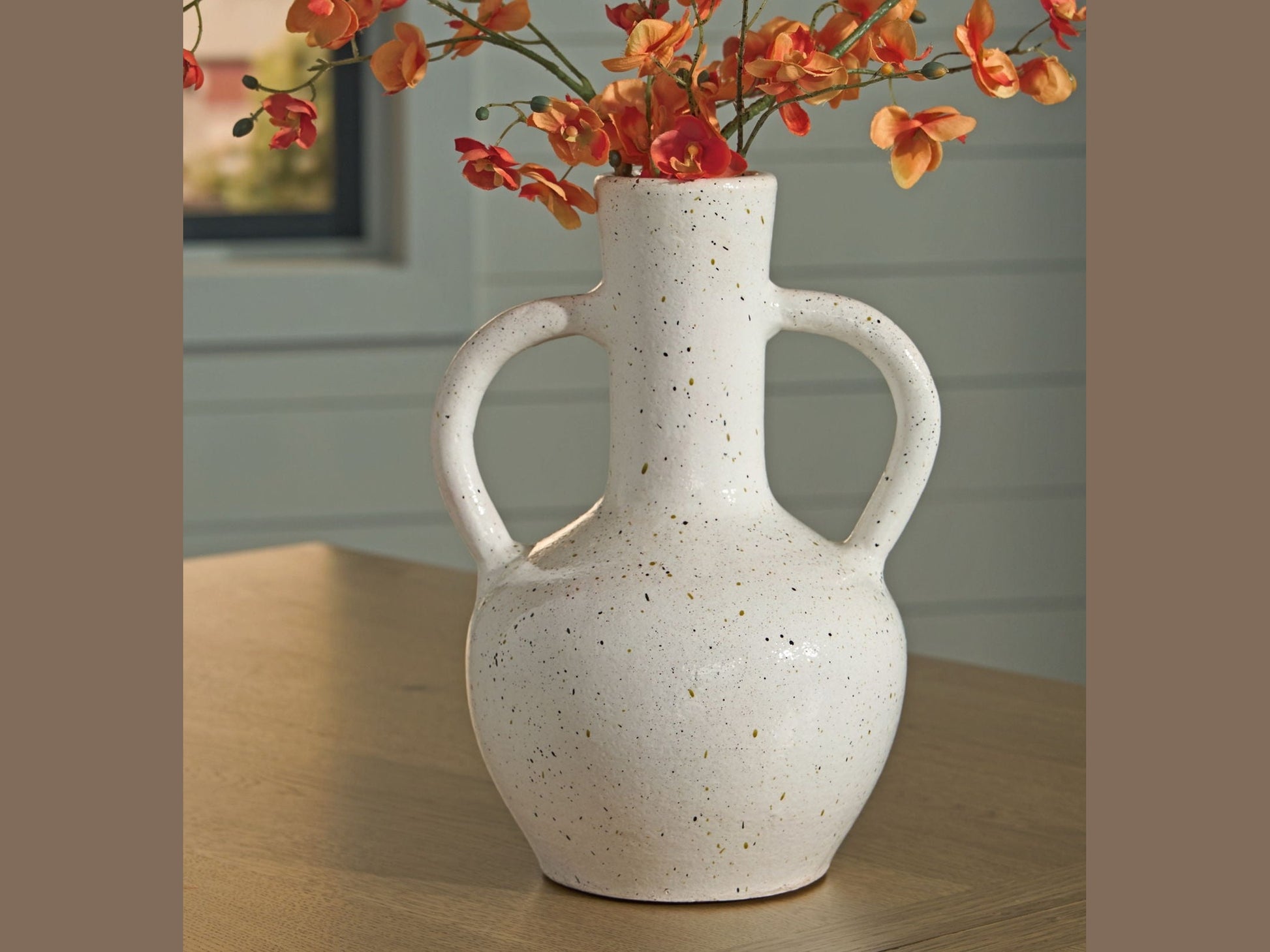 Dallinworth white speckled vase with orange and red flowers on a wooden surface