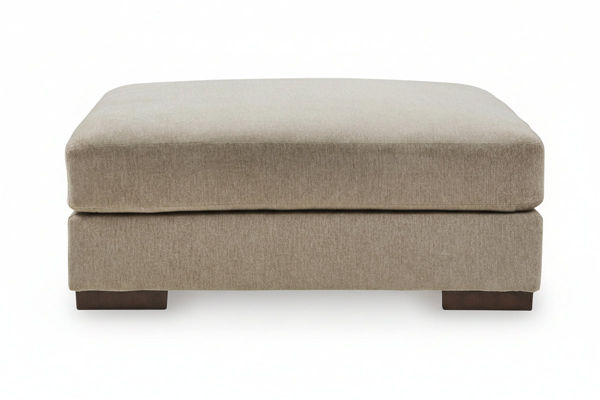 A modern two-tiered upholstered ottoman in a textured beige fabric, supported by dark brown wooden feet, shown against a plain white background.