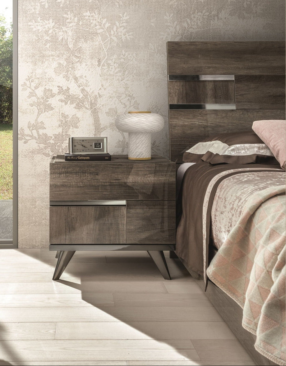A modern bedroom furniture set featuring a dark wood nightstand and matching headboard with built-in silver metallic shelf accents, styled with neutral bedding and a small table lamp.