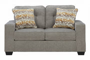 Gray loveseat with patterned pillows on a white background