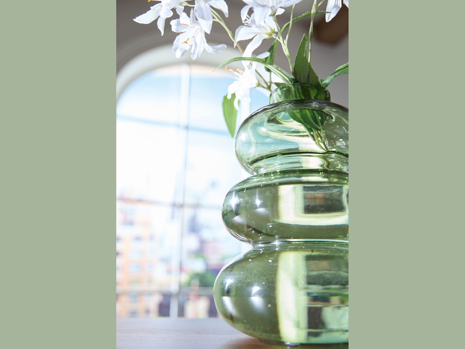 Clear glass vase with stacked cylindrical shapes containing white flowers.