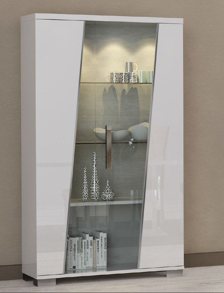A tall white high-gloss display cabinet with two glass doors and interior shelves, shown against a plain beige wall and light floor.