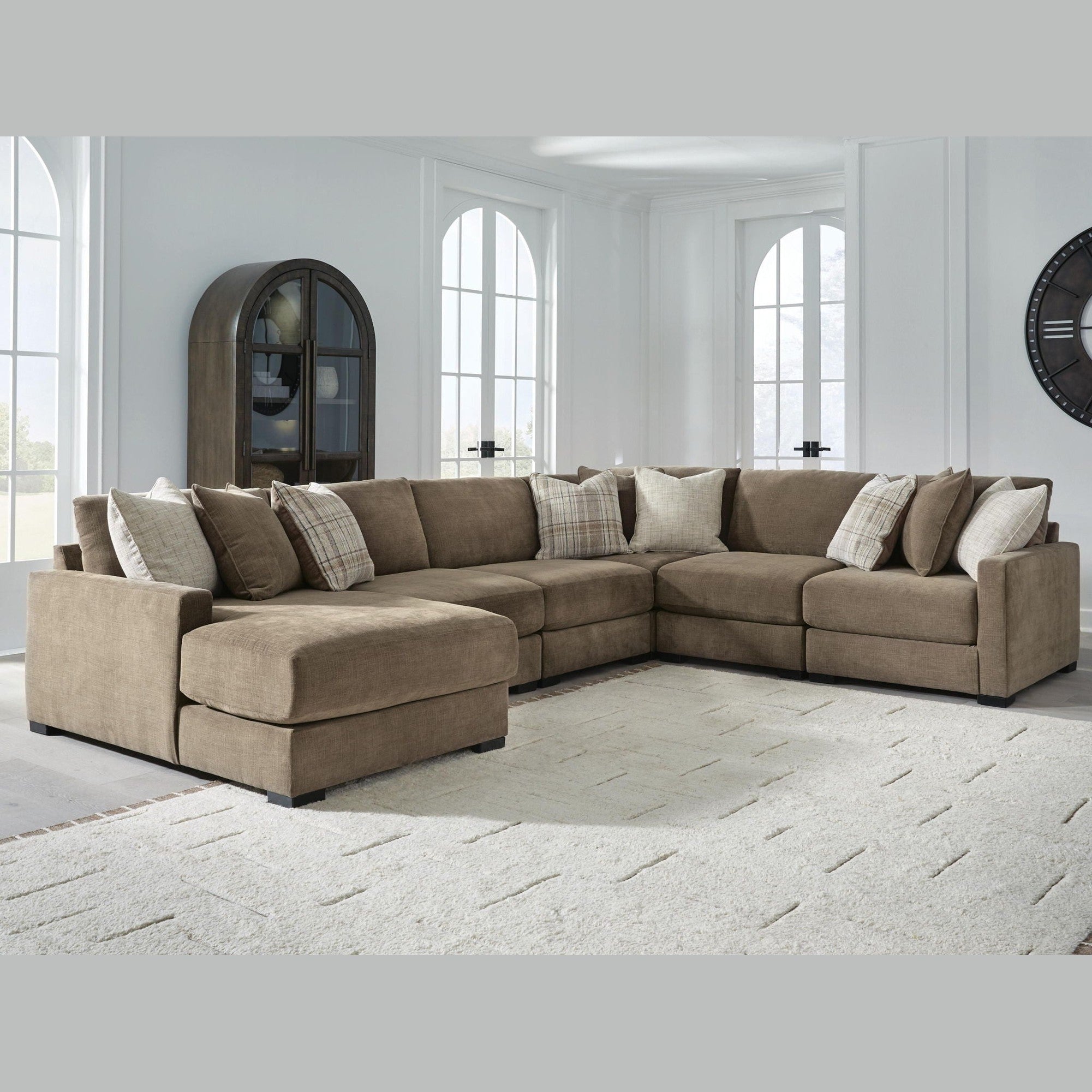 Brown sectional sofa with patterned cushions in a bright living room.