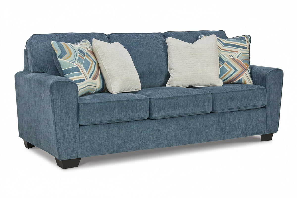 Blue sofa with patterned and plain cushions on a white background