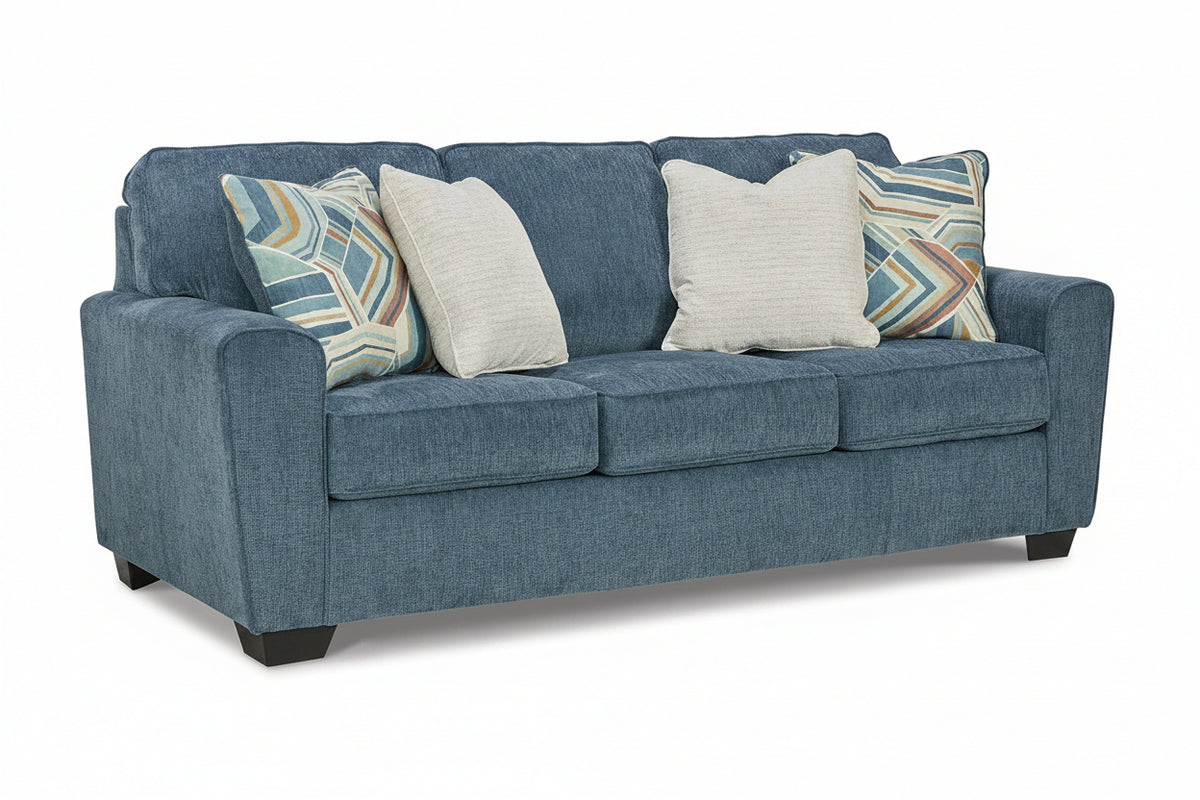 Blue sofa with patterned and plain cushions on a white background