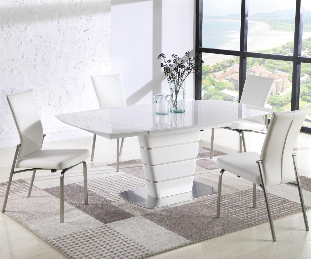 Modern white dining table with chairs in a room with large windows.