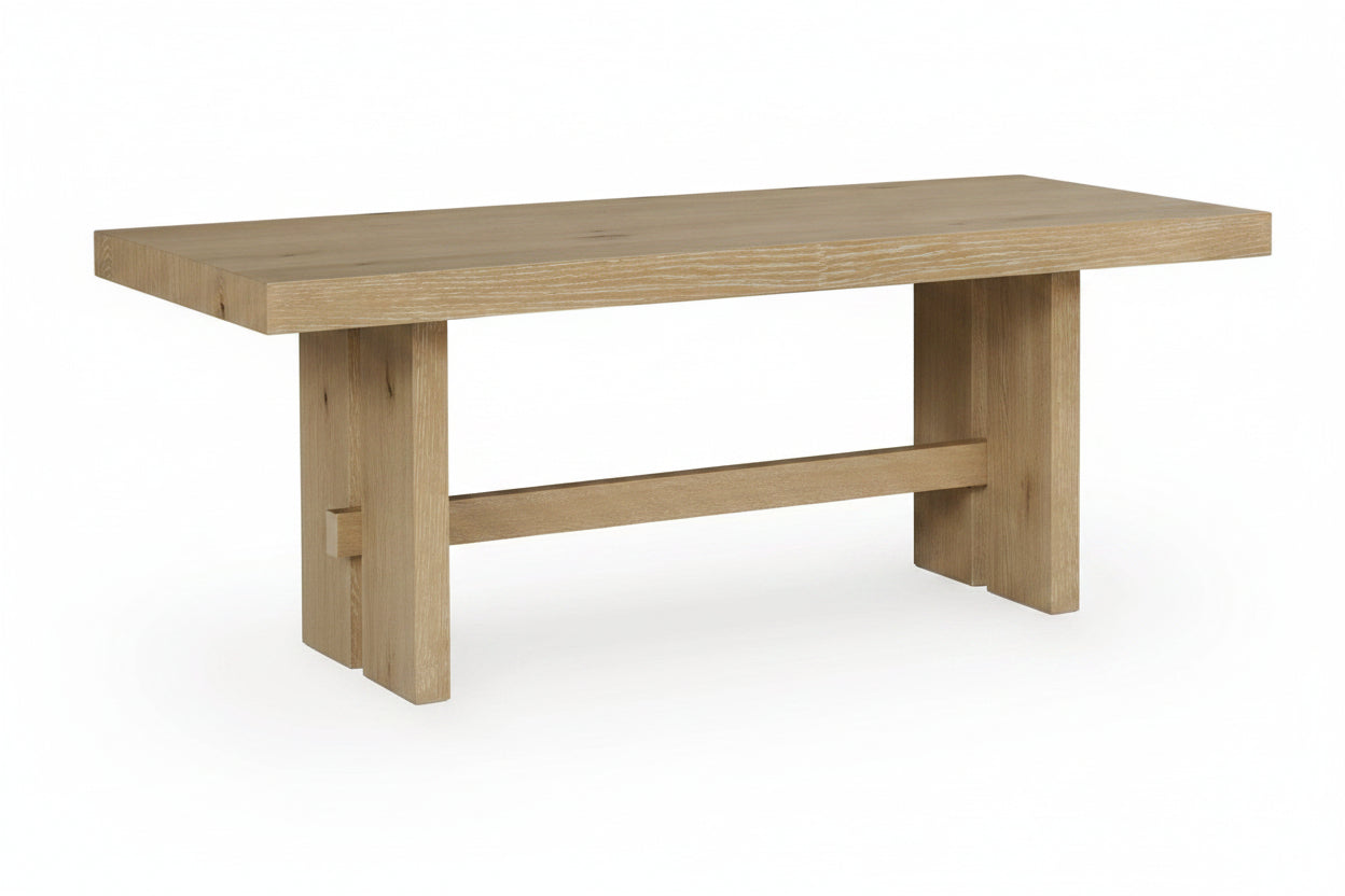 A light oak wood dining table with a thick rectangular top and a trestle-style base, shown against a plain white background.
