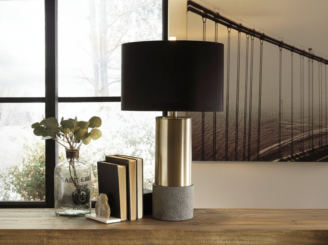 Jacek modern lamp with black shade and gold base on a wooden surface with decorative items.