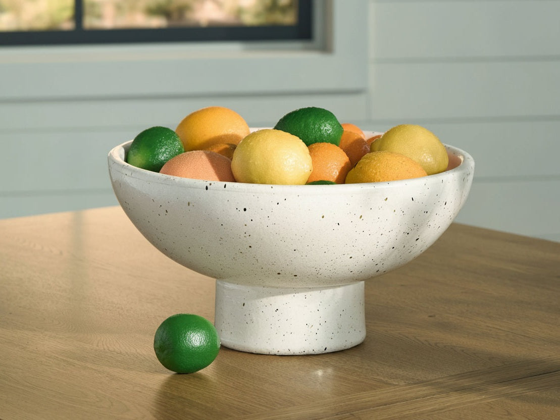 White speckled ceramic bowl filled with fruits on a wooden surface
