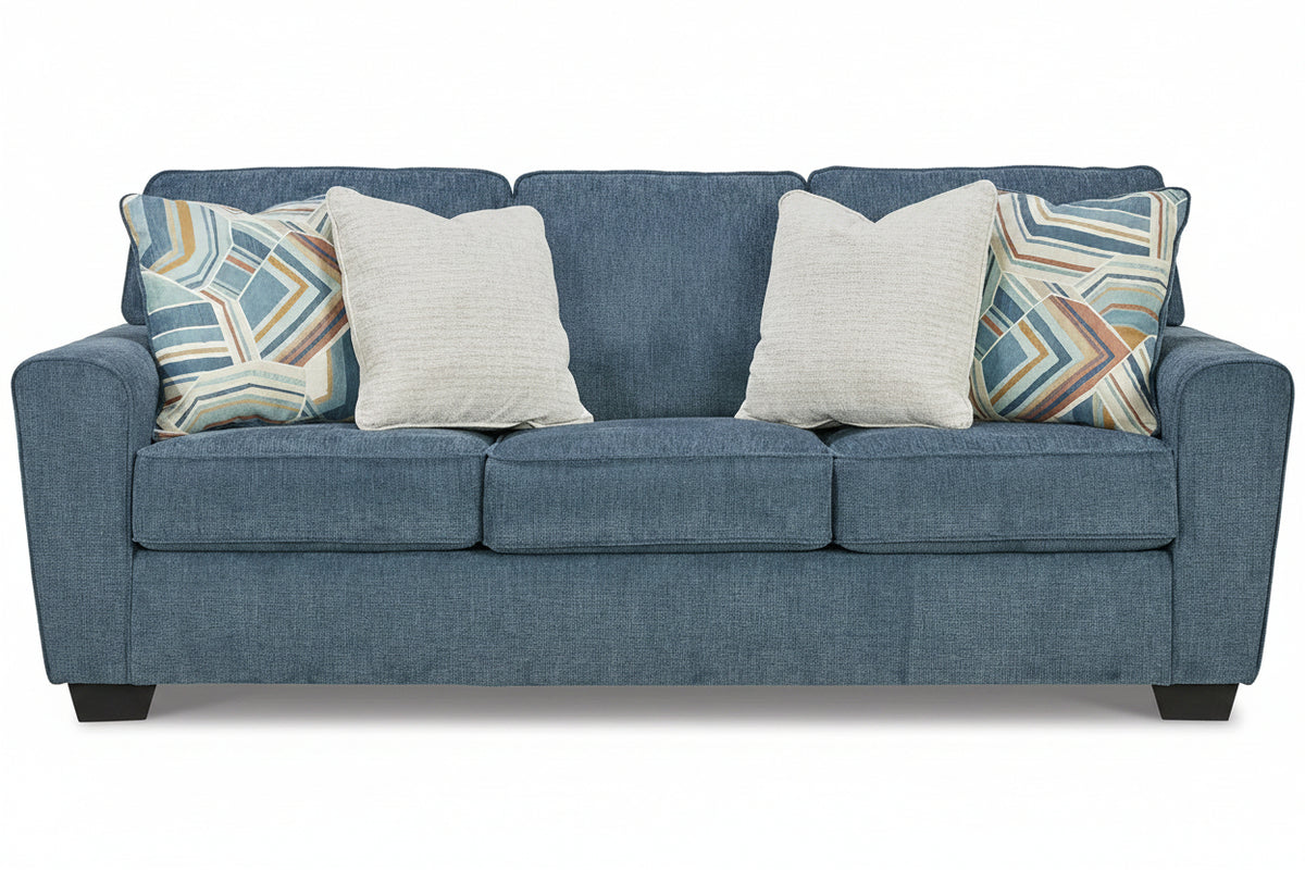 Blue sofa with patterned and plain pillows on a white background
