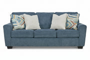 Blue sofa with patterned and plain pillows on a white background