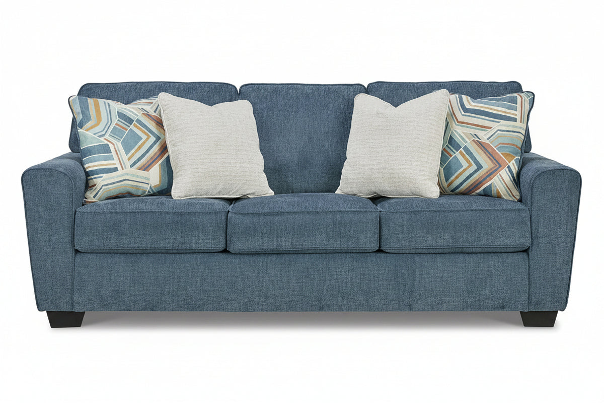Blue sofa with patterned and plain pillows on a white background