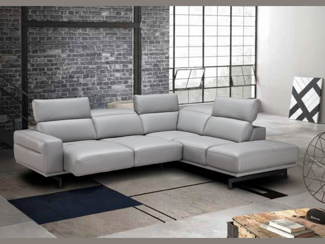 Gray sectional sofa in a modern room with brick wall and large window.