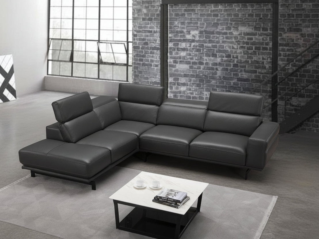 Gray sectional sofa in a modern room with brick wall and large window.