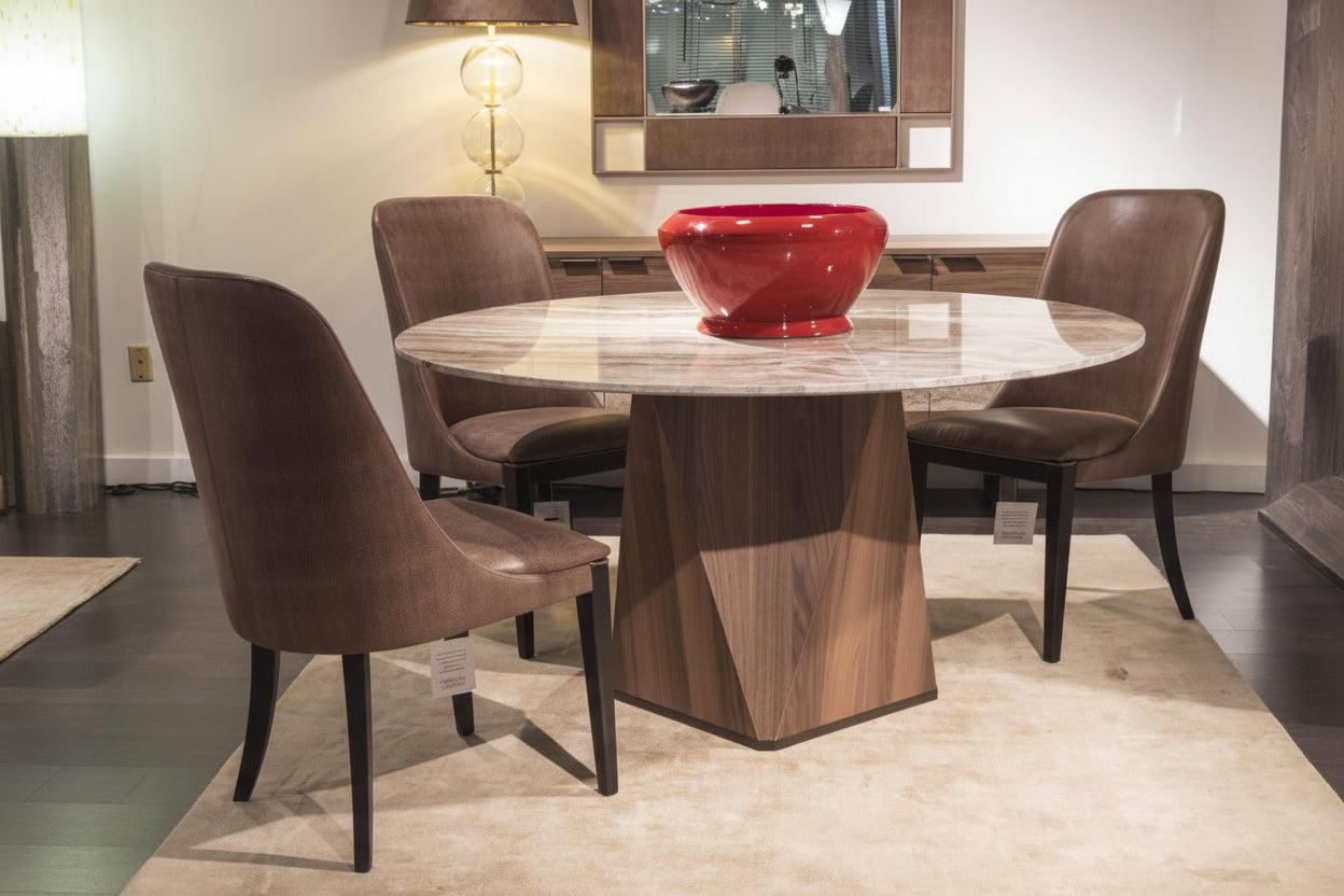 Diamond dining table with a round marble top and brown chairs, featuring a red bowl on the table.