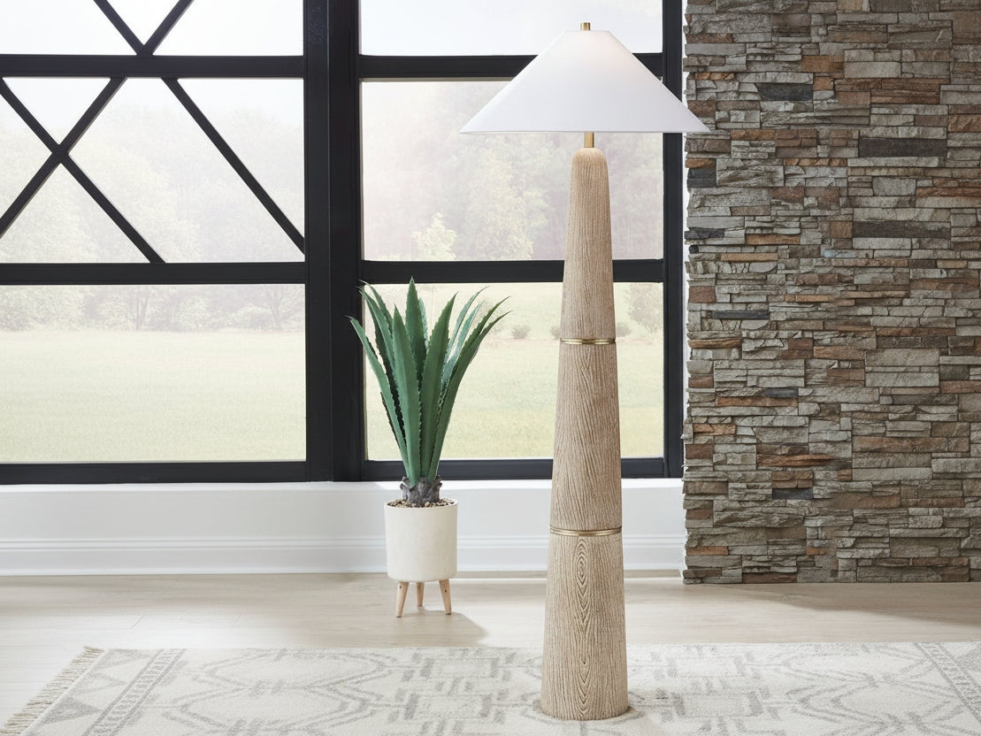 Gasparleigh tall floor lamp with a textured base in a room with a stone wall and large window.
