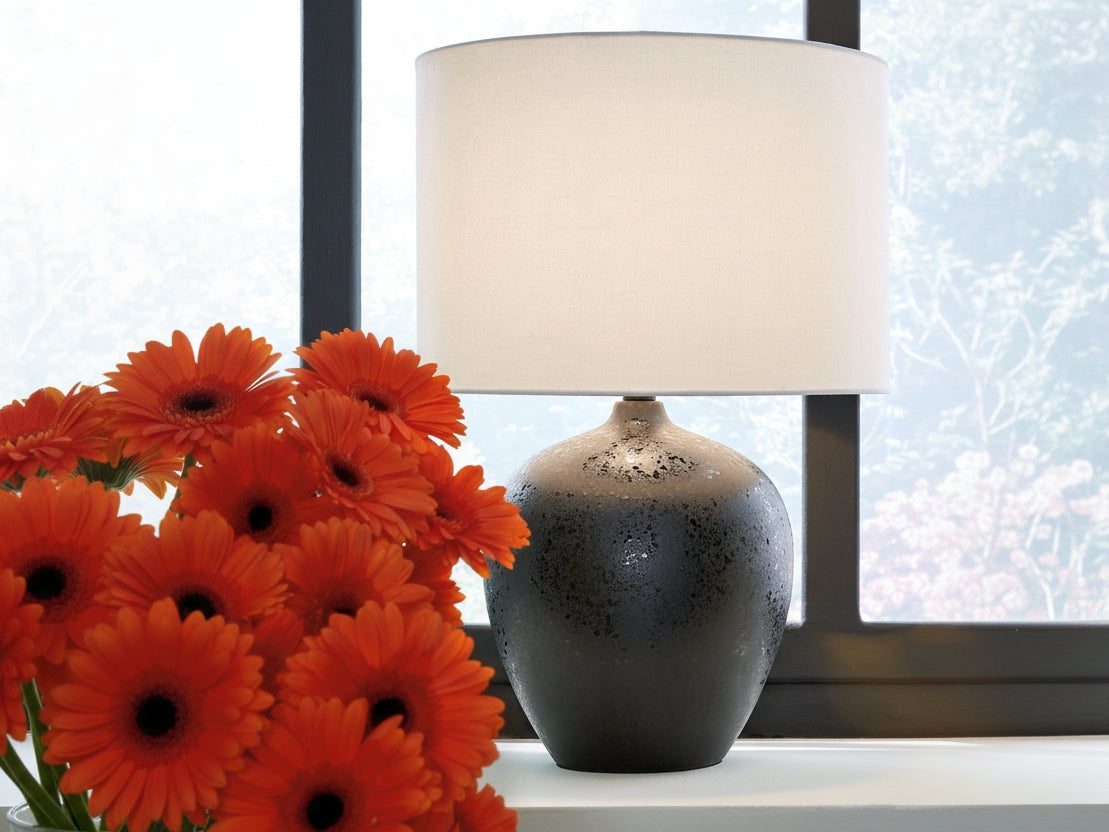 Ladstow black ceramic lamp with white shade next to orange flowers on a windowsill