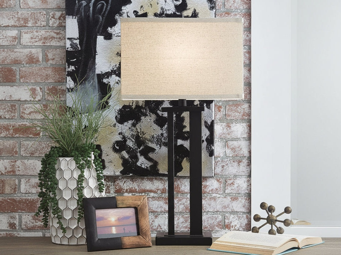 Aniela table lamp with a decorative background featuring a cowhide rug and framed picture.