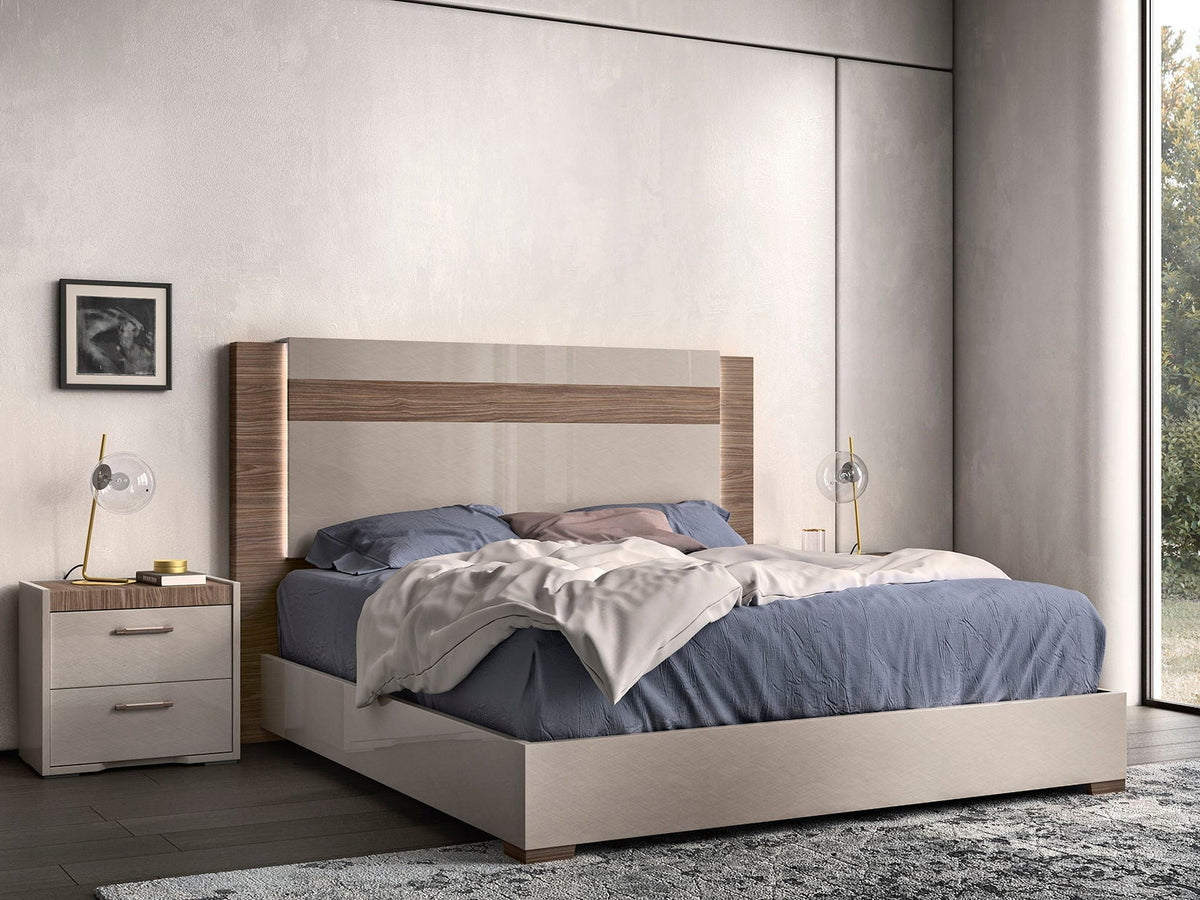 A modern platform bed with a light beige upholstered frame and a wood-grain accent panel on the headboard, styled with blue bedding and a white throw blanket in a contemporary bedroom setting.
