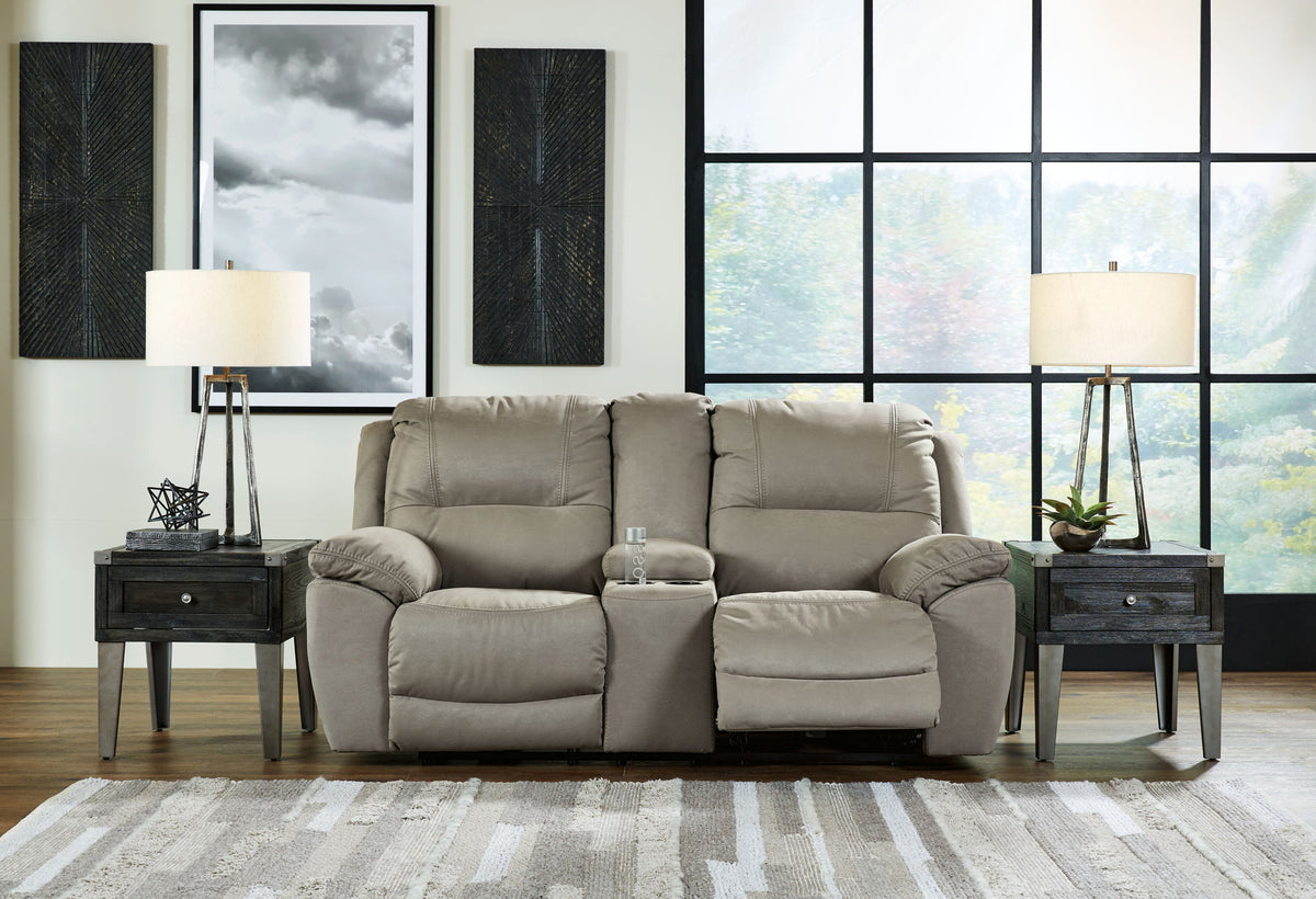Gray reclining sofa in a living room with large windows and decorative elements.