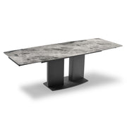 Grand extendable dining table with marble-like top and black legs on a white background.
