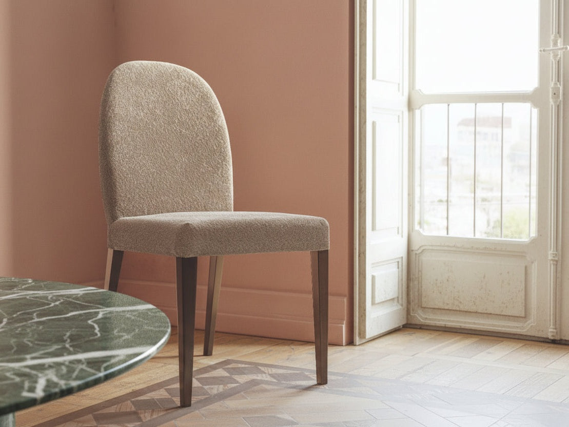 Hebe beige upholstered chair against a pink wall with a large window.