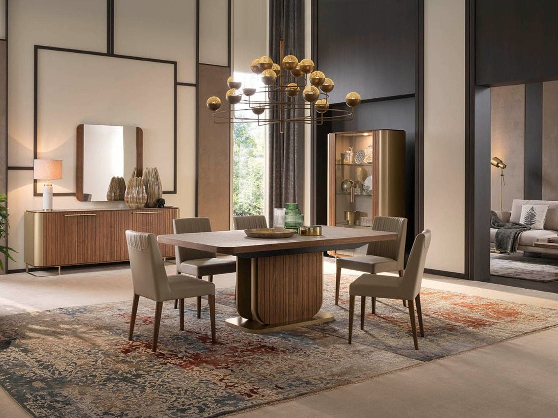 The Hera modern dining room with a wooden table and chairs, a large mirror, and decorative elements.
