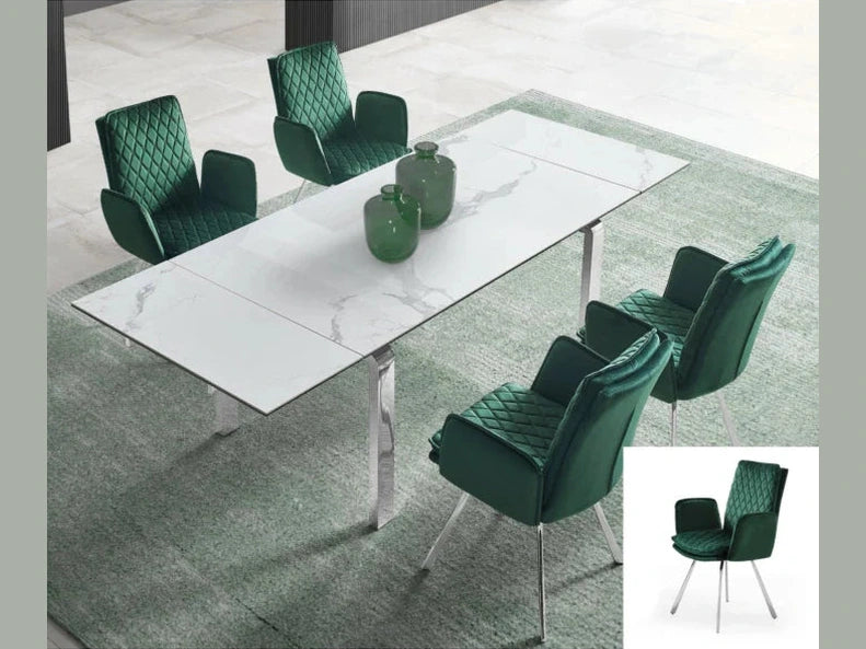 Four emerald green quilted velvet armchairs with silver legs surround a sleek white marble dining table on a textured green area rug.