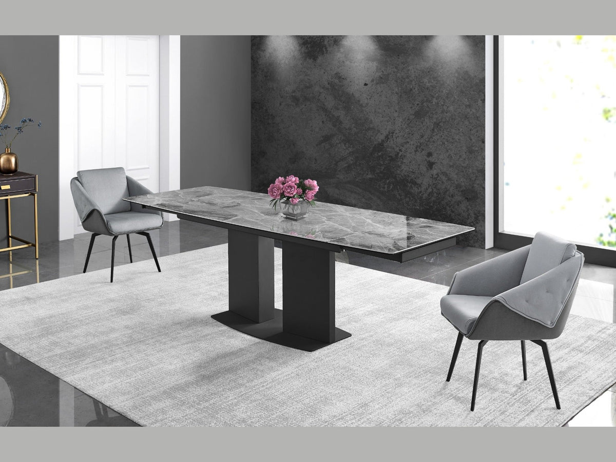 A modern grey marble-top dining table with a black pedestal base anchors a contemporary dining room featuring sleek grey upholstered chairs and a textured area rug.