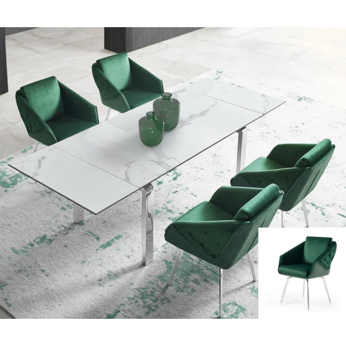 Four emerald green velvet armchairs surround a modern white marble dining table on a textured grey and green rug.