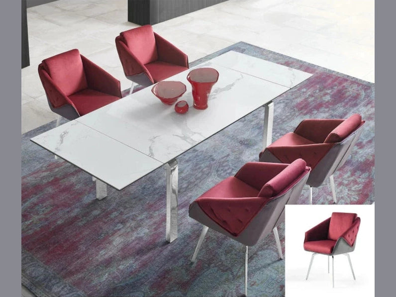 Four plush red velvet dining chairs surround a modern extendable white marble table on a textured purple and red area rug.