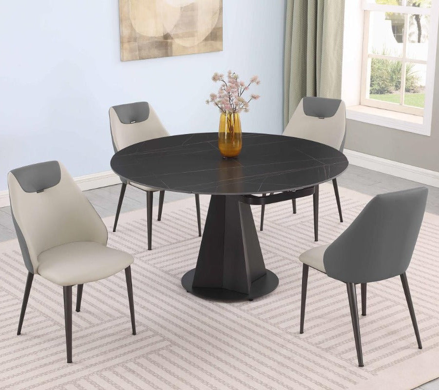 Joycelyn dining room set with a round black table and four chairs in a well-lit room.