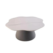 A modern coffee table features a scalloped white marble top resting on a thick charcoal grey pedestal base.