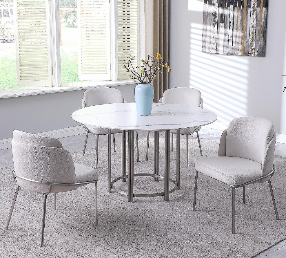 Kamila dining room set with a round marble table and four chairs in a modern interior setting.