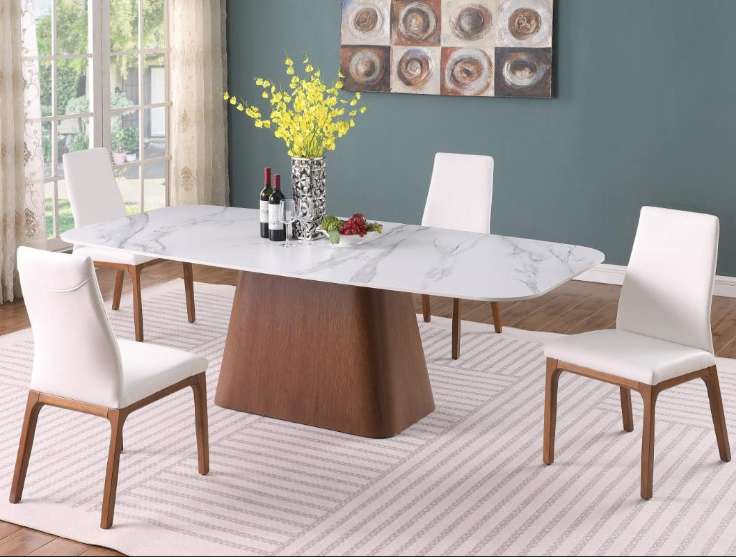 The Kenza Rosario dining room set with a marble table and white chairs, featuring a vase of yellow flowers.