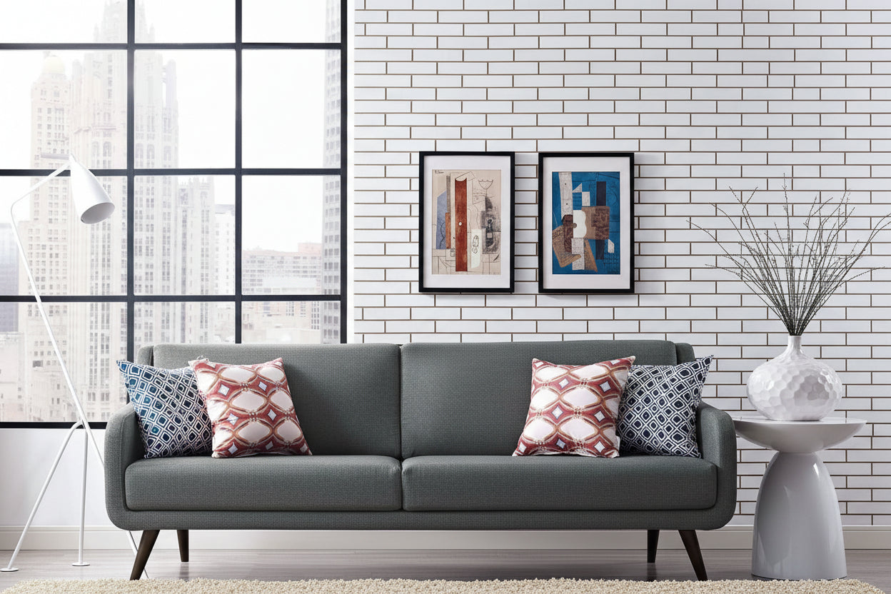 Verve Gray sofa with patterned cushions in a modern living room with a white brick wall and large windows.
