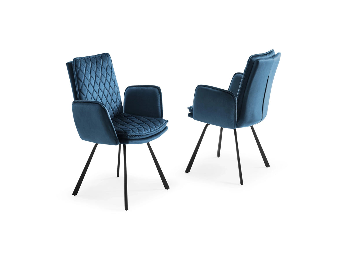Two modern blue velvet dining armchairs feature elegant diamond-quilted stitching and tapered black metal legs against a clean white background.